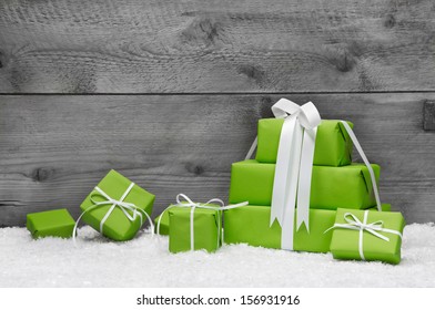 Stack Of Green Christmas Presents, With Snow On Grey Wooden Background