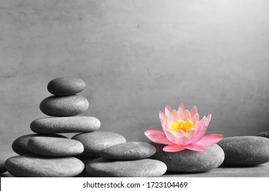 Stack Of Grey Massage Stones On Grey Background And Lotus Flower. Spa Concept.