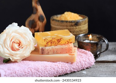 Stack of handmade soap bars on a pink towel. Rose flowers near them.