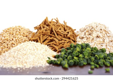 Stack of Healthy High Fiber Prebiotic Grains including wheat bran cereal, oat flakes and pearl barley, on rustic dark wood table background with white background.