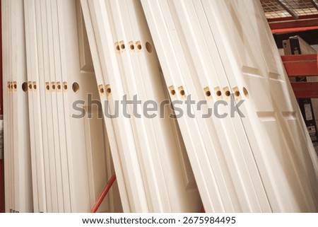 Stack of hollow core white interior doors with pre-drilled lockset holes at hardware store aisle in Dallas, Texas. Lightweight, economical mass production ready for installation, renovation uses. USA