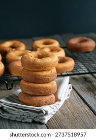 Stack of homemade donuts with cooling rack in background
