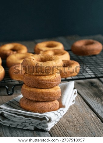 Stack of homemade donuts with cooling rack in background