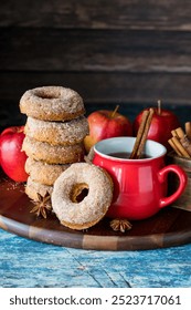 A stack of homemade doughnuts served with spiced hot apple cider.