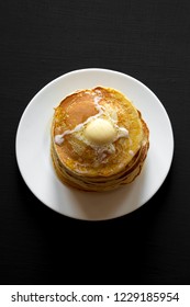 Stack Of Homemade Pancakes With Butter On White Plate On Black Table, Top View. Overhead, From Above.