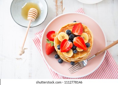 Stack Of Homemade Pancakes With Strawberries, Banana And Blackberries On A Pink Plate. Top View