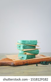 Stack of homemade spirulina popsicles on parchment paper and a wooden cutting board, healthy dessert concept, These healthy frozen treats represent a nutritious dessert option