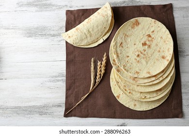 Stack of homemade whole wheat flour tortilla on napkin, on wooden table background