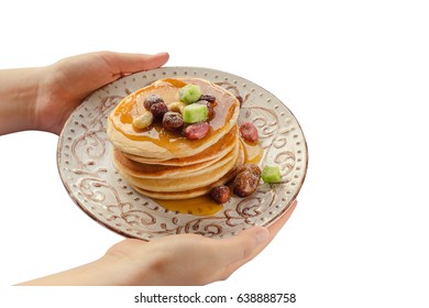 Stack of hot pancakes with nuts and dried fruits in woman hands. Isolated