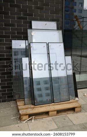 Stack of insulated glass window panes on wooden pallet near modern building facade