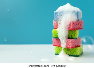 Stack of kitchen cleaning sponges with soap bubbles on blue background. Front view