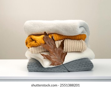 Stack of knitted clothes decorated with autumn leaf, woolen sweaters. - Powered by Shutterstock