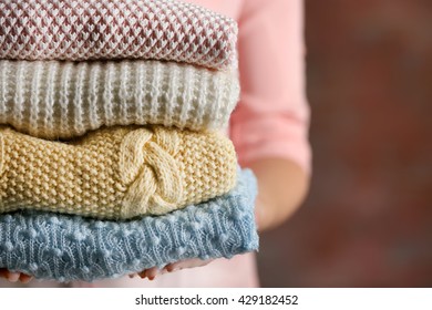Stack of knitted clothes in female hands closeup - Shutterstock ID 429182452