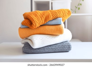 Stack of knitted folded clothes on table.Knittings pile.Autumn clothing heap.Woolen sweaters.