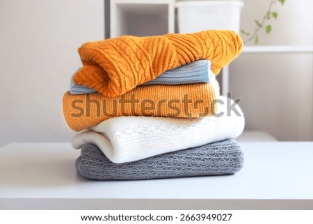 Stack of knitted folded clothes on table.Knittings pile.Autumn clothing heap.Woolen sweaters.