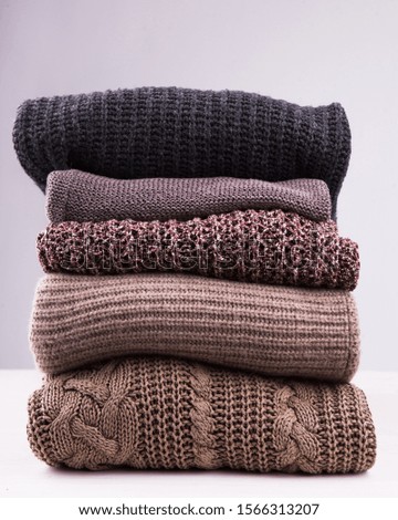 A stack of knitted winter sweaters on a white background.