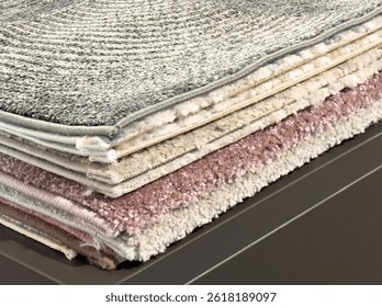 Stack of layered textured carpets with varied patterns and colors for interior design.