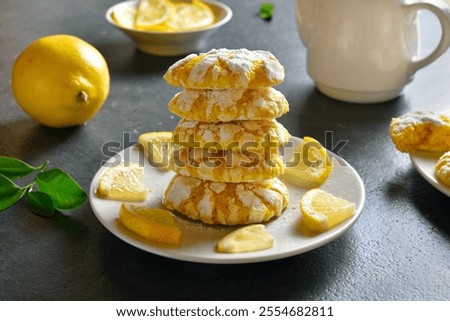 Stack of lemon crinkle cookies on plate on blue stone background. Close up view