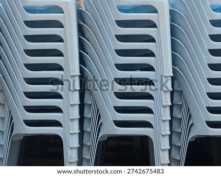Stack of light blue plastic chairs neatly piled up, showing an efficient space-saving storage solution and ready for use at events