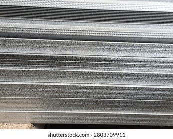 Stack of lightweight galvanized steel truss profiles for roof framing at a construction site, side view of stacked metal spandek or galvalume channels for residential house building