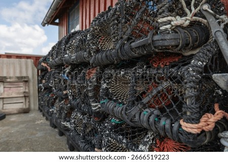Stack of lobster and crab pots outside a red wooden fishing hut on the Danish seashore
