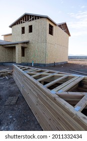 Stack of lumber pieces next to an almost finished home in a new neighborhood