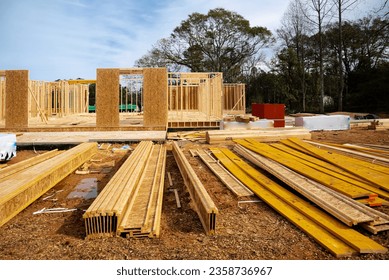 Stack of lumbers in front of timber frame house with post, beam, OSB (Oriented Strand Board) plywood sheathing residential home under construction suburbs Atlanta, Georgia. Suburban American building - Shutterstock ID 2358736967