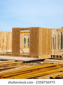 Stack of lumbers in front of timber frame house with post, beam, OSB (Oriented Strand Board) plywood sheathing residential home under construction suburbs Atlanta, Georgia. Suburban American building - Shutterstock ID 2358736975
