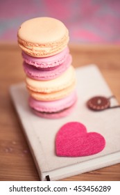 Stack of macaroons staying on book with felt heart closeup. Selective focus