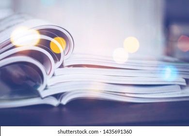 Stack of magazine on wooden table in dark room with bokeh light effected