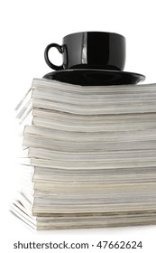 Stack of magazines and black cup of coffee isolated on white background.