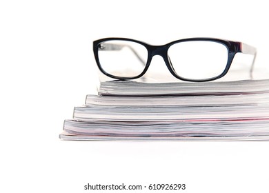 Stack of magazines and eyeglasses.