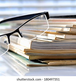Stack of magazines with glasses