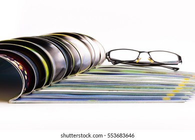 Stack of magazines with glasses on top.