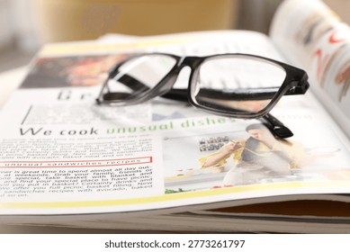 Stack of magazines and glasses on white table indoors, closeup
