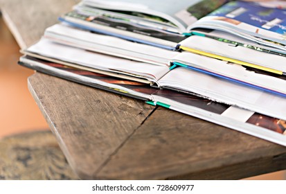 Stack of magazines on wood table.