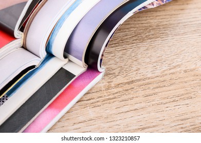 Stack of magazines on wooden table.