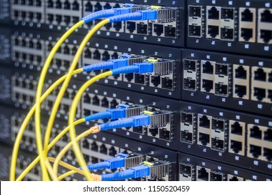A stack of managed Internet switches is connected by fiber optic cables. Server equipment of the main technical platform. The concept of high-speed information transfer. - Shutterstock ID 1150520459