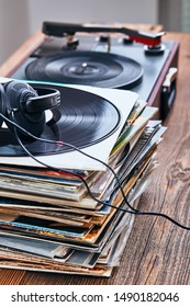 Stack of many black vinyl records, turntable vinyl player and headphones put on the stack. Classic stereo set. Candid people, real moments, authentic situations