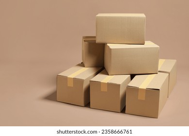 Stack of many cardboard boxes on light brown background, space for text