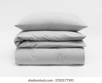 Stack of matte gray bed linen on a white background, a pillow separate from a blanket, bedding items on a white background, a mock-up of bed linen. Front view photo