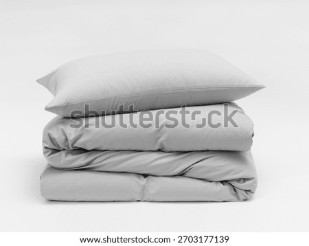 Stack of matte gray bed linen on a white background, a pillow separate from a blanket, bedding items on a white background, a mock-up of bed linen. Side view photo