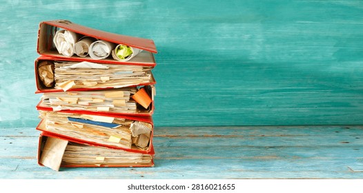 stack of messy files and ringbinders, red tape, bureaucracy,messy office, overworked staff business concept. Large free copy space, negative space technique