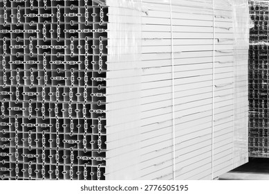 Stack of metal structural parts with square cross-section and many small holes. Industrial constructions for building background
