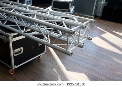 Stack of metal trusses for mounting the stage.  A metal truss lies on a box. Сonstruction stage.