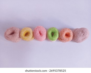 A stack of mini donuts (or coconut candy) and round sweets in pastel colors (pink, yellow, green, orange). A typical Indonesian market snack.