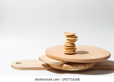 A stack of mini pancakes balanced on a stack of wooden serving boards. On a white background, horizontal frame with space, hard shadows