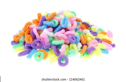 A Stack Of Miniature Pony Tail Holders On White Background.