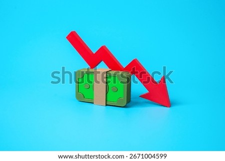 A stack of money and an arrow pointing down. A drop in income, salary cut, financial loss, reduced profits, economic downturn, recession effects, money shortage