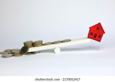 Stack Of Money Weighing Down A Scale. Cost Of Owning A Home Imbalance Concept.